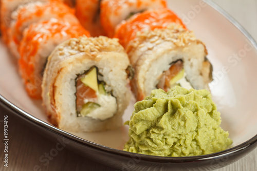 Close up wasabi and sushi rolls - Uramaki with Conger, Uramaki California on the background. Japanese cuisine