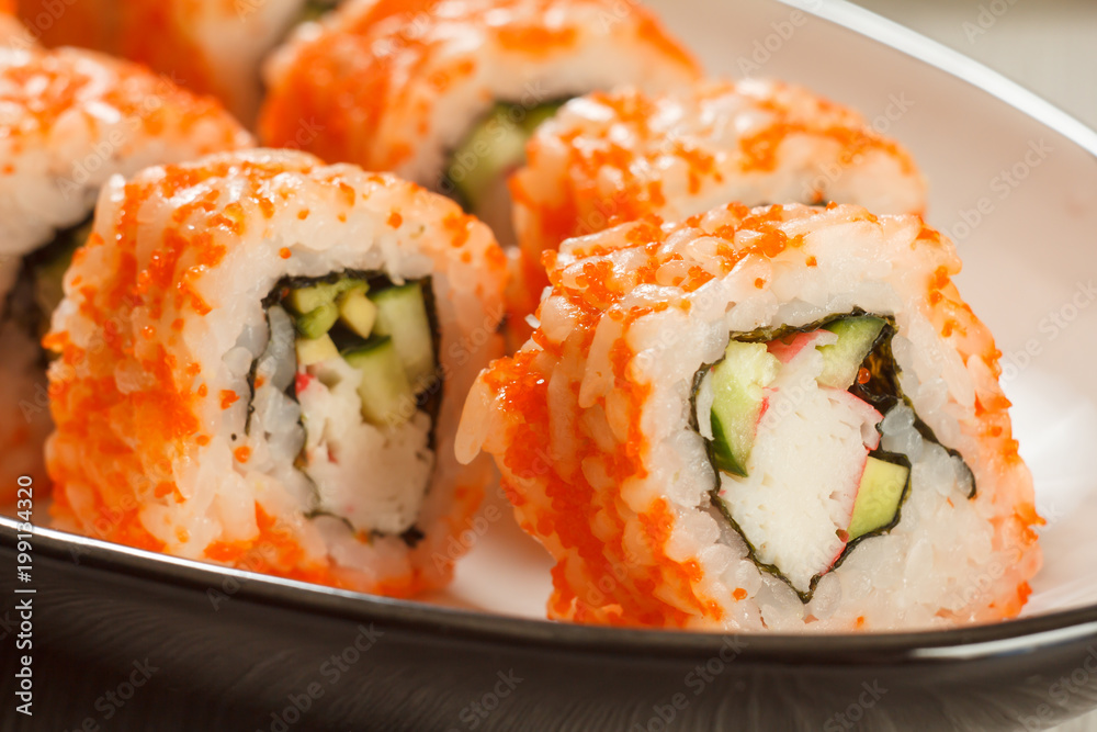 Close up Uramaki California. Sushi rolls with nori, rice, pieces of avocado, cucumber, crab sticks and flying fish roe Close up Uramaki California. Sushi rolls with nori, rice, pieces of avocado, cucumber, crab sticks and flying fish roe