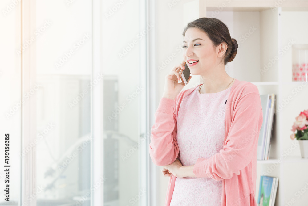 Business woman standing working near a window and holding call talking by phone at office. Business woman standing working near a window and holding call talking by phone at office.