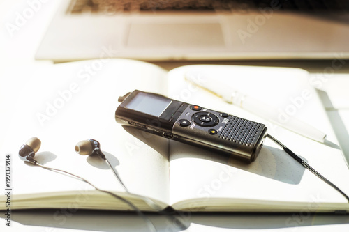 Wallpaper Mural Dictaphone with headphones on a light worktable of a journalist with a notebook, a green succulent and a laptop. In the sunlight Torontodigital.ca