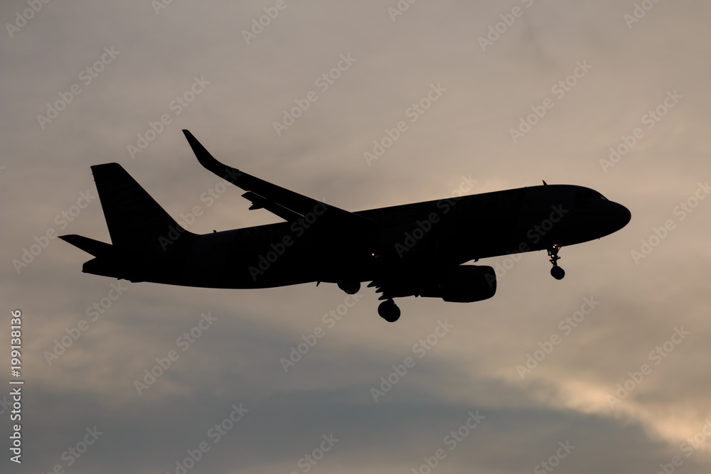Silhouette passenger airplane flying away in to sky high altitude on sunset Silhouette passenger airplane flying away in to sky high altitude on sunset