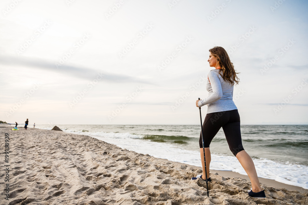 Nordic walking - young woman working out on beach