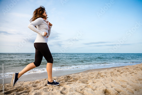 Young woman running, jumping on beach