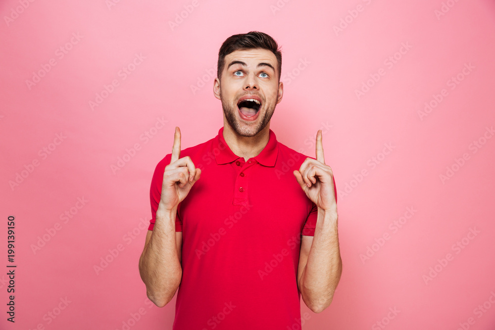 Portrait of a joyful young man pointing fingers up Portrait of a joyful young man pointing fingers up