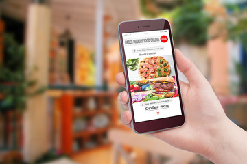 Female hand holding smartphone and ordering food with app in restaurant