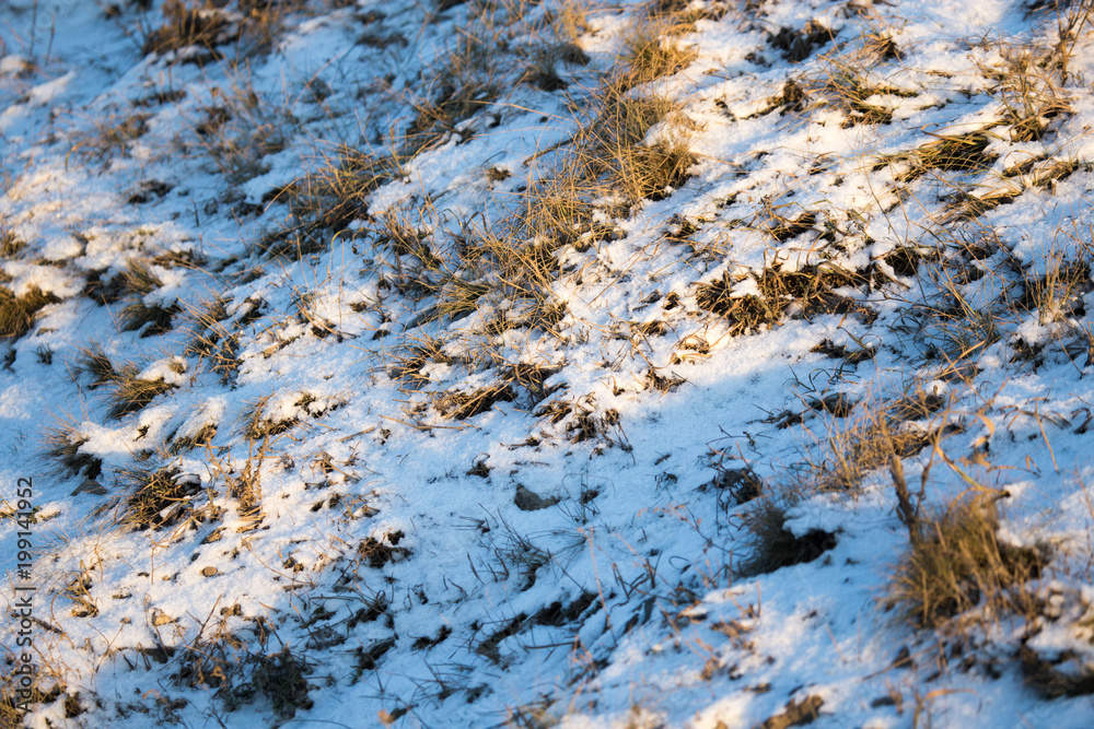 Snow on the ground in the rays of the sunset as a background