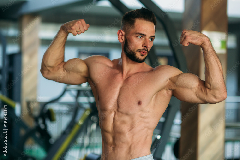 A young athlete trains in the gym. Shows the muscles A young athlete trains in the gym. Shows the muscles