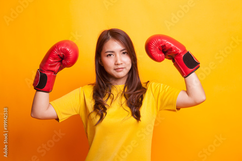 Young Asian woman with red boxing gloves in yellow dress