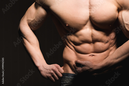 Fitness concept. Muscular and fit torso of young man having perfect abs, bicep and chest. Male hunk with athletic body.