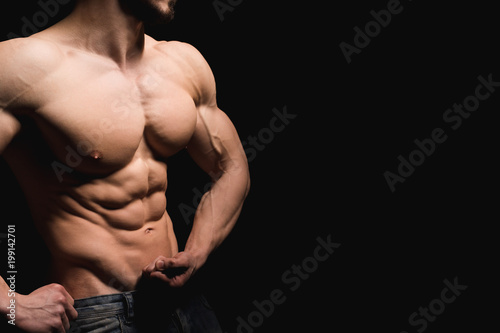 Fitness concept. Muscular and fit torso of young man having perfect abs, bicep and chest. Male hunk with athletic body on black background. Copypaste space