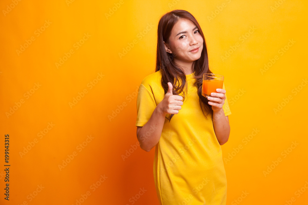 Young Asian woman thumbs up drink orange juice in yellow dress Young Asian woman thumbs up drink orange juice in yellow dress