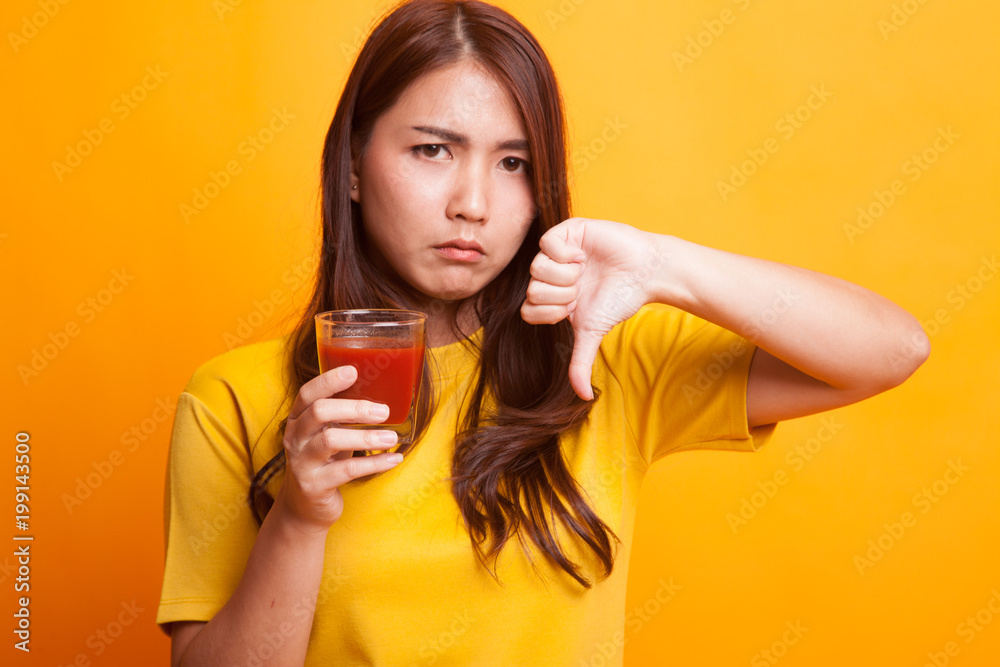 Asian woman thumbs down hate tomato juice in yellow dress Asian woman thumbs down hate tomato juice in yellow dress