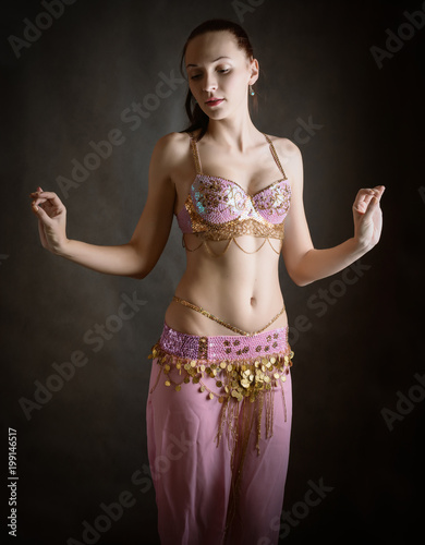 Exotic belly dancer woman with perfect body on a dark background.