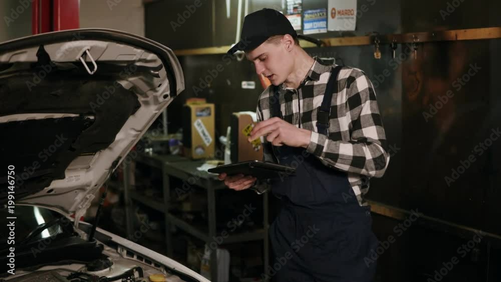 Mechanic inspects the car undercarriage way with a digital tablet Mechanic inspects the car undercarriage way with a digital tablet