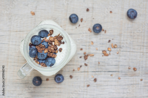Natural yogurt with granola, berries on the wooden table top view selective focus