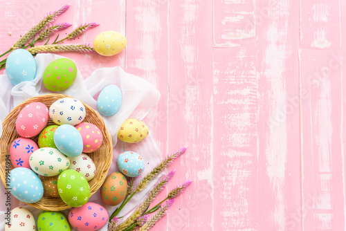 Happy easter! Colorful of Easter eggs in nest with paper star, flower and Feather on pastel color bright pink and white wooden background.