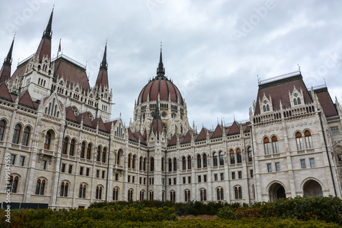 Budapest parliament with bushes in front with cloudy sky