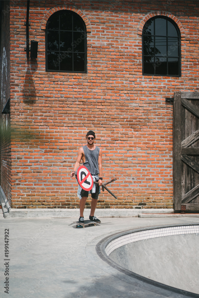 handsome skater holding road sign near skatepark handsome skater holding road sign near skatepark