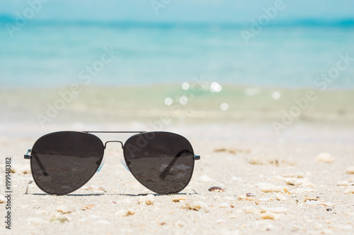 Selective focus Fashion sunglasses on sea beach under clear blue sky.Travel relax vacation - Andaman sea, white sand, Summer holiday relax background with copy space.