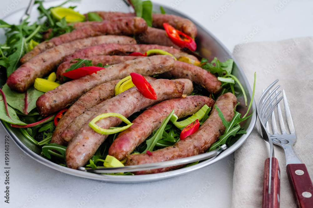 Grilled sausages with vegetables, fresh herbs and spices on white background. Grilled sausages with vegetables, fresh herbs and spices on white background.