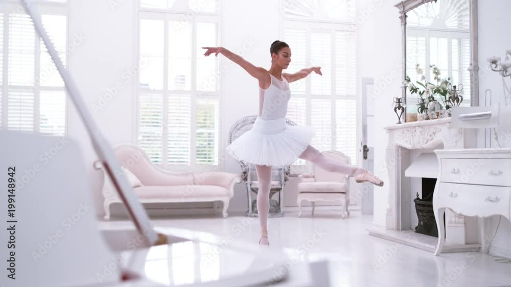 Graceful ballerina practicing ballet in white studio, slow motion Graceful ballerina practicing ballet in white studio, slow motion