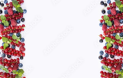 Black-blue and red fruits. Ripe currants, raspberries, blackberries and blueberries on white background. Berries at border of image with copy space for text.