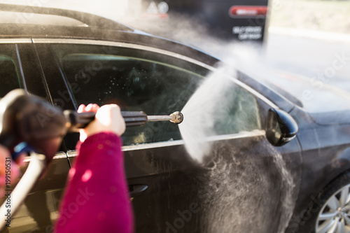 Car washing. Cleaning car using high pressure water. Selective focus.