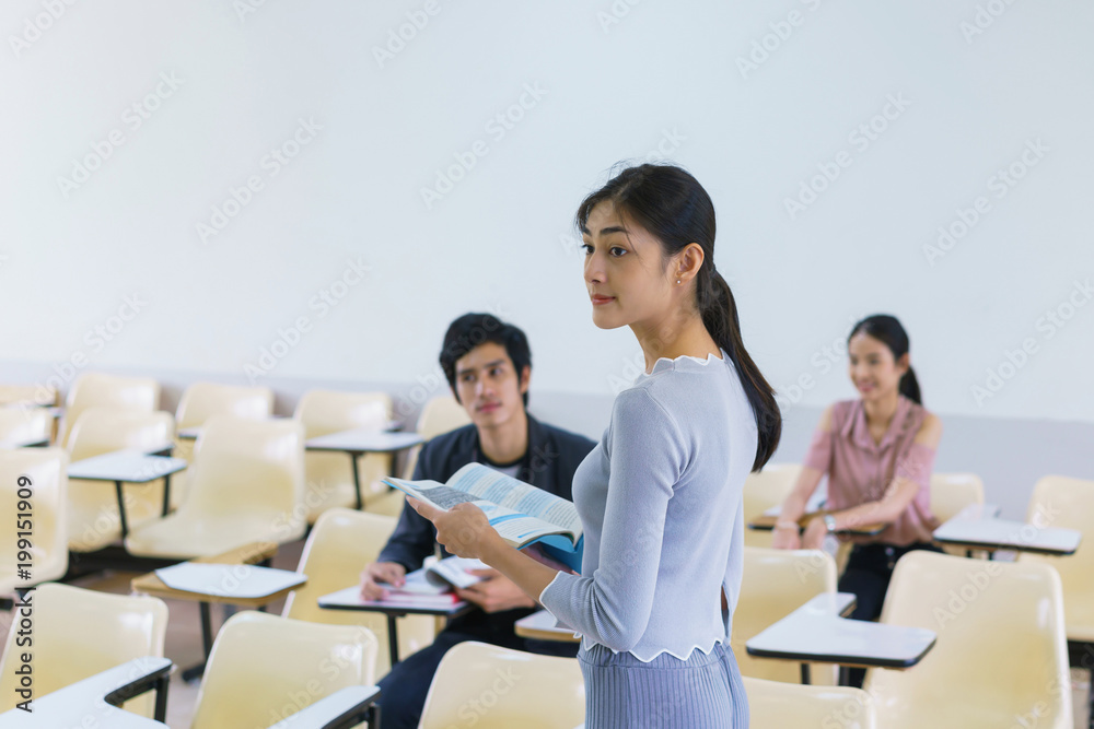 Young woman standing present friend student in a classroom showing ready answer. concept of education. Young woman standing present friend student in a classroom showing ready answer. concept of education.