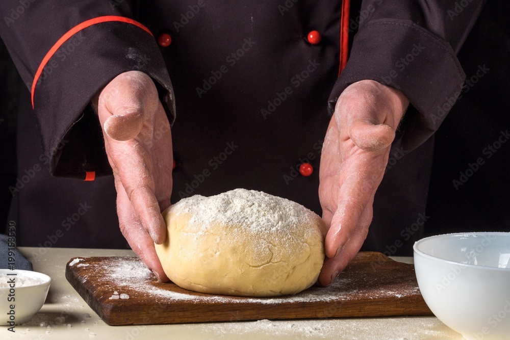 Cook with dough in a dark jacket. Cooking in the restaurant.