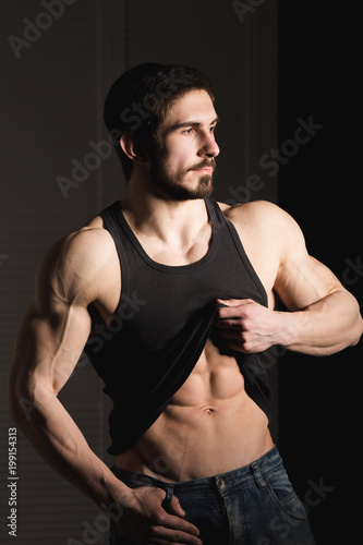 Perfect man shows his six pack abs. Muscular and fit torso of young male. Hunk with athletic body holding shirt, striptease.