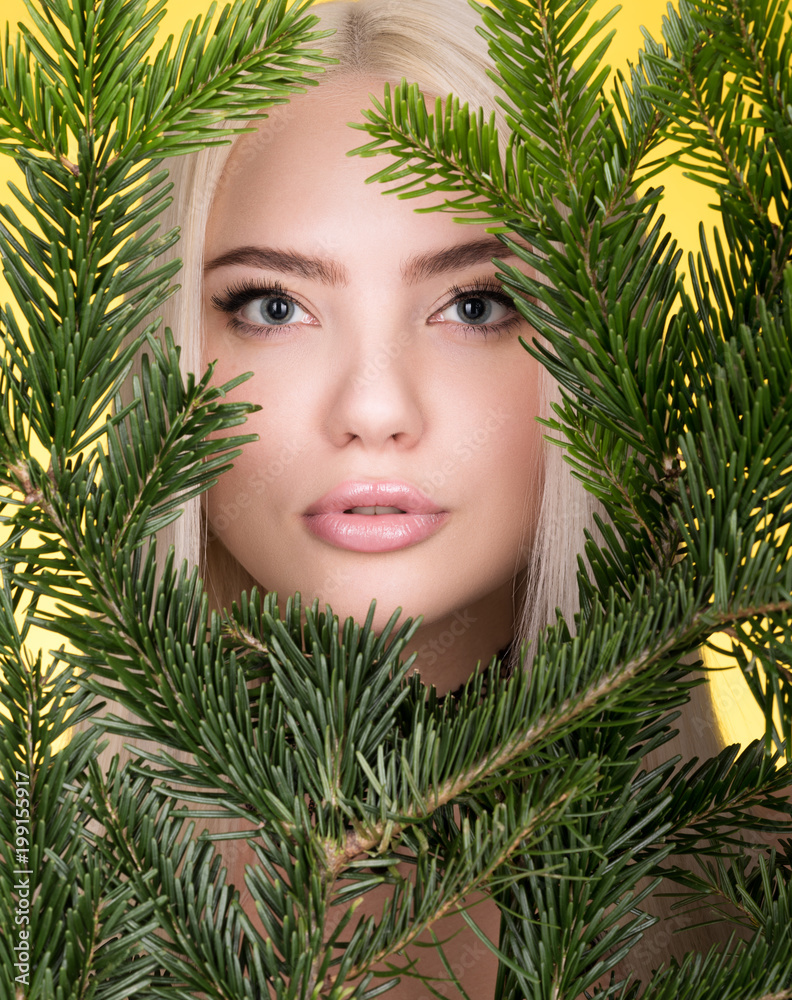 Beauty portrait of beautiful young woman in the branches of a spruce. Perfect clear skin, professional make-up Beauty portrait of beautiful young woman in the branches of a spruce. Perfect clear skin, professional make-up