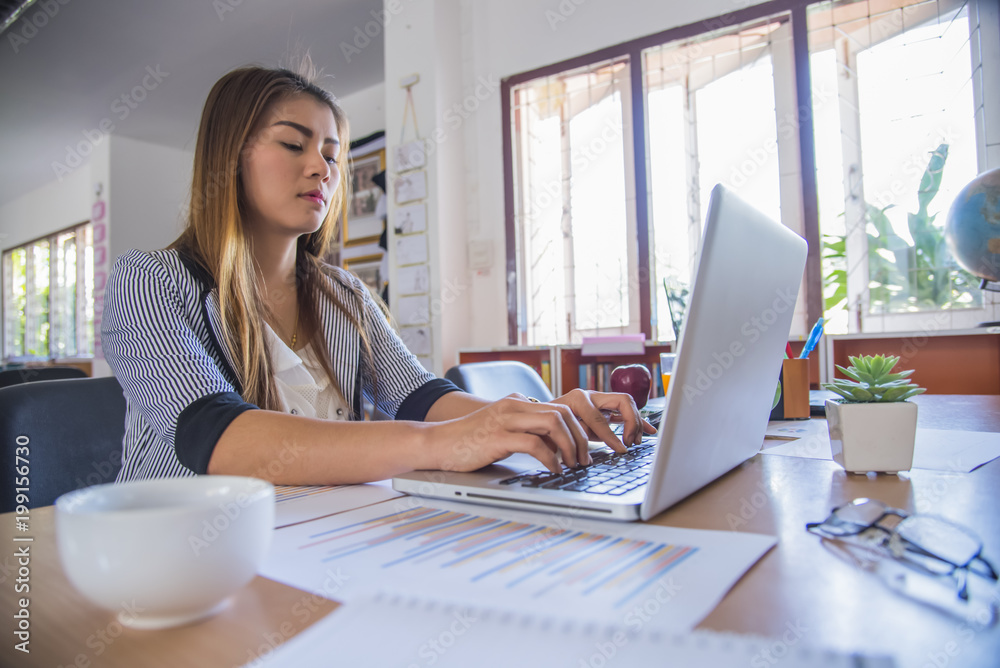 Portrait of business woman with laptop, finance graph and writes on a document at her office. Portrait of business woman with laptop, finance graph and writes on a document at her office.