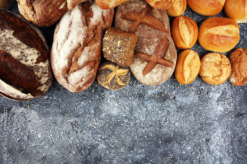 Different kinds of bread and bread rolls on board from above. Kitchen or bakery poster design Different kinds of bread and bread rolls on board from above. Kitchen or bakery poster design