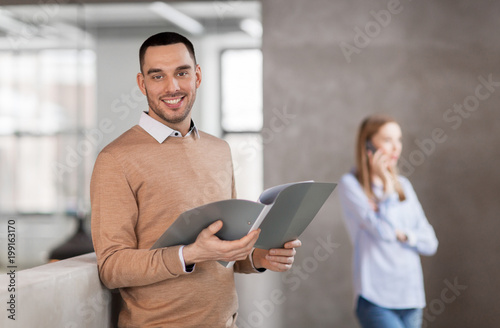 business  people and corporate concept - smiling male office worker with folder