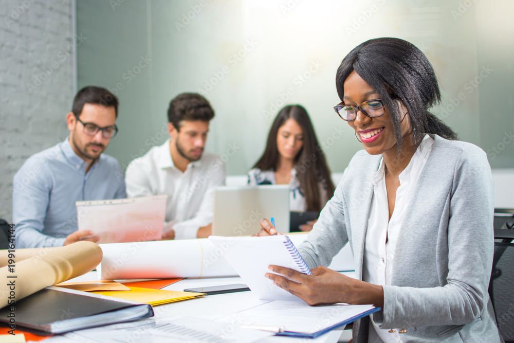 Smiling business woman taking notes to notebook while sitting in her workplace Smiling business woman taking notes to notebook while sitting in her workplace