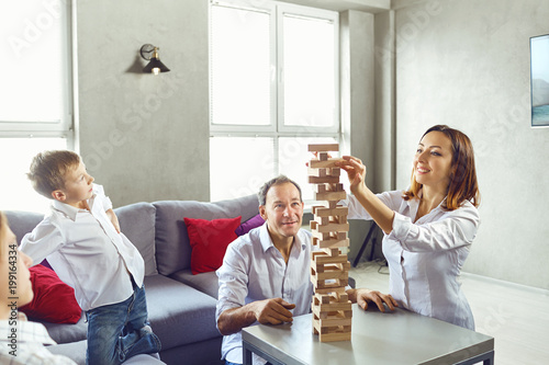 The family plays board games gaily while sitting at the table inside the room.