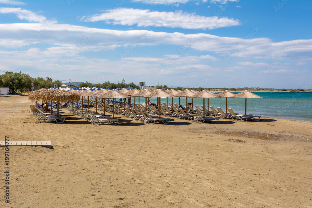 Umbrellas and sunbeds on beach in summer. Naxos island. Cyclades, Greece.