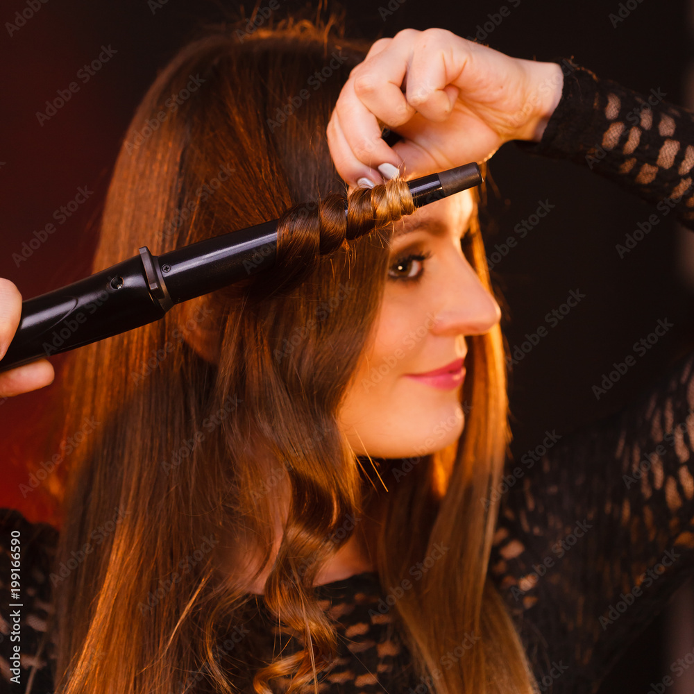 Obraz premium Happy woman curling her long brown hair