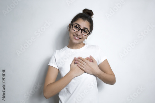 A young woman showing her cordial thanksgiving by holding her hands near the heart. The girl expresses sincere, benevolent and honest emotions. Language of the body.  photo
