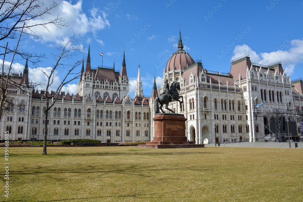 Budapest parliament with a rider statue and blue sky