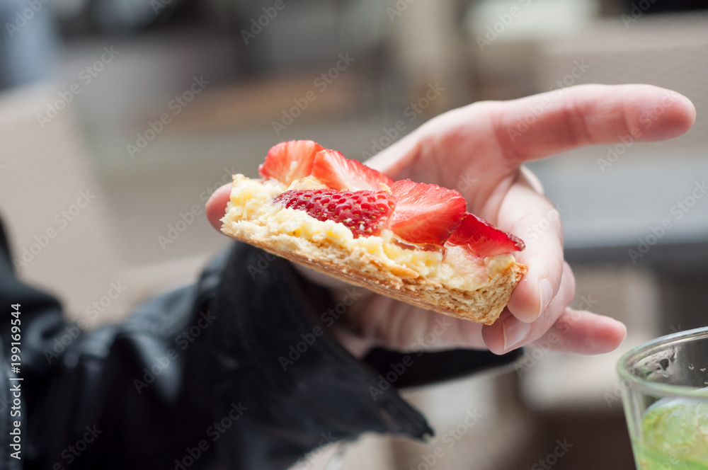 closeup of woman eating strawberry tart in outdoor closeup of woman eating strawberry tart in outdoor