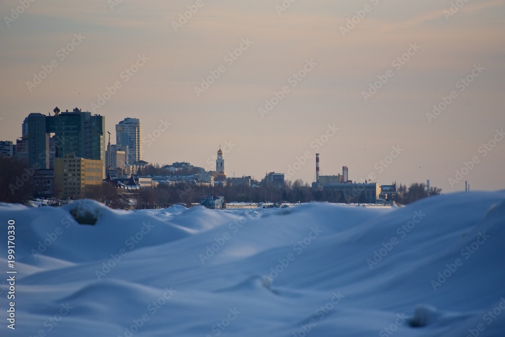 High buildings of the big city on horizon and blue snow before. Abstract winter landscape.