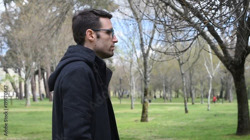 Hombre joven con gafas de perfil paseando por el campo