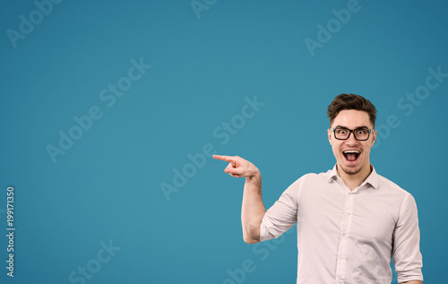 Young hipster man in glasses pointing happily away