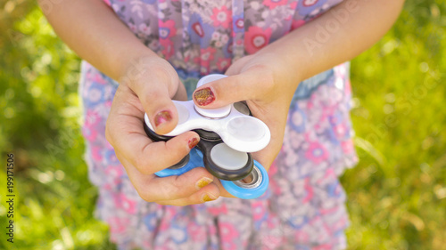 The girl is holding spinners white, blue and black colour. Stress relieving toy. photo