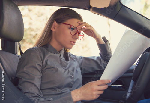 Upset woman reading paper in car