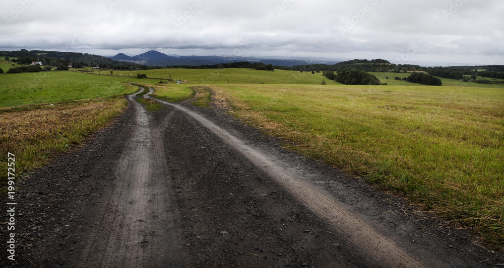 Dirt road between open field.