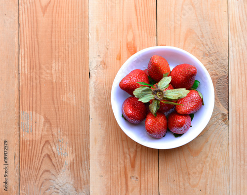 a bowl of strawberries on the wooden background