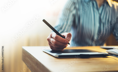 graphic designer working at office with digital stylus on background monitor computer, hipster manager using device pen, female hands graw on portable tablet, work process concept in workplace