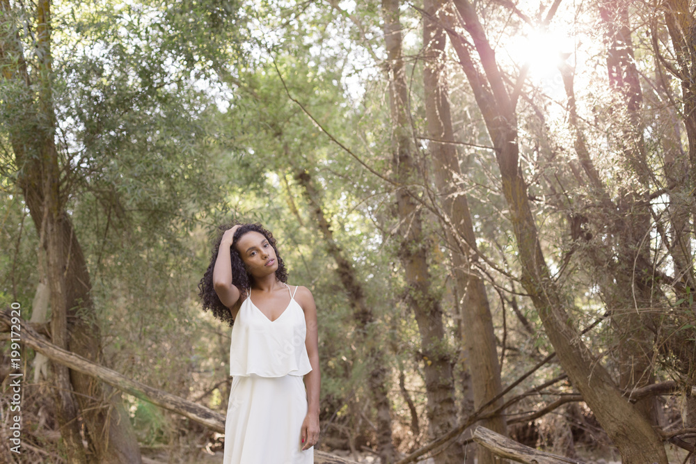 portrait outdoors of a beautiful young afro american woman at sunset. Green background. Lifestyle portrait outdoors of a beautiful young afro american woman at sunset. Green background. Lifestyle